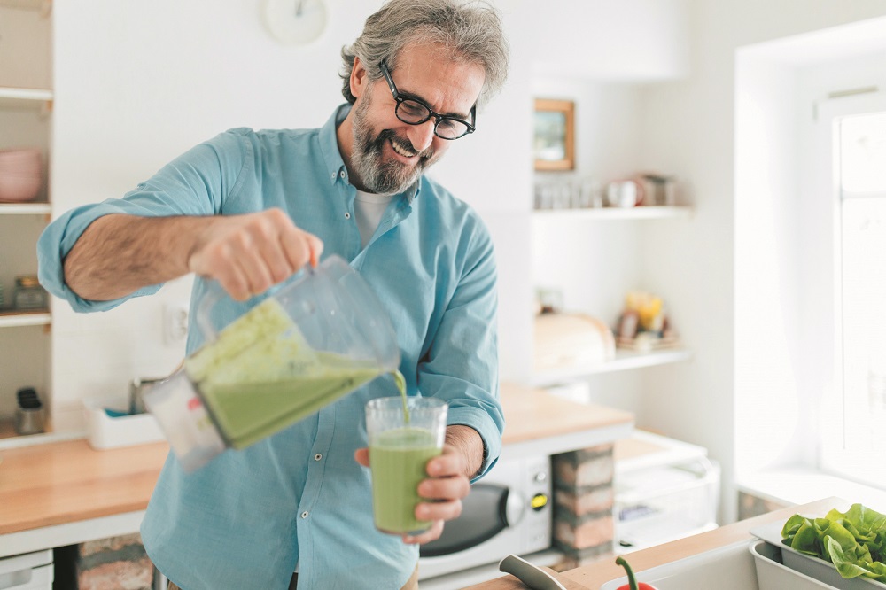 Senior man preparing smoothie in kitchen