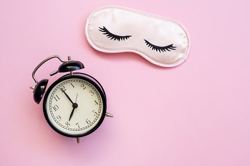 Healthy sleep concept with mask, alarm on black