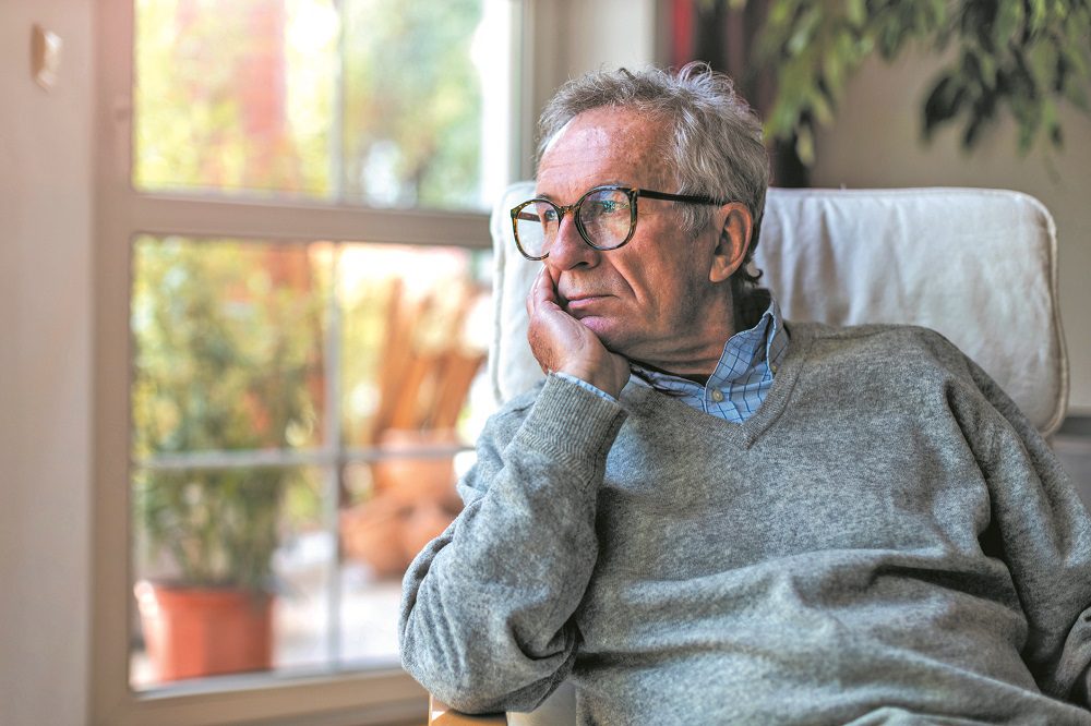 Senior man looking out of window at home