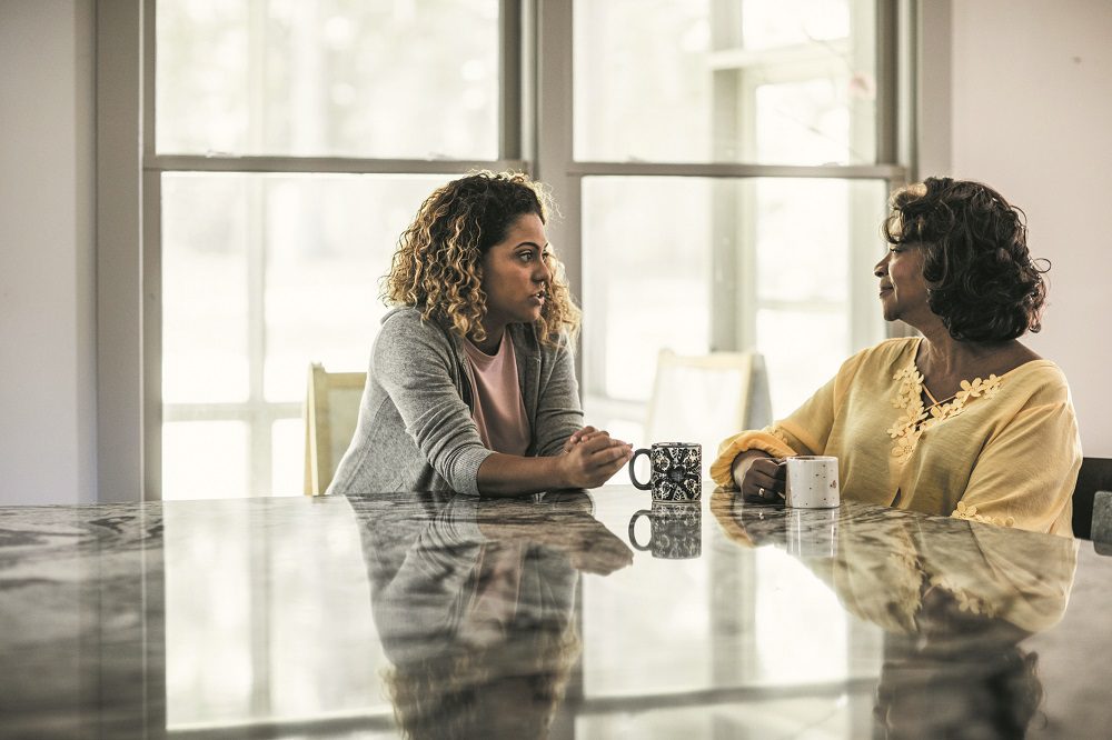 Mother and adult daughter laughing in kitchen