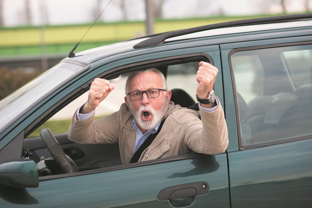 Senior man in car road rage in traffic