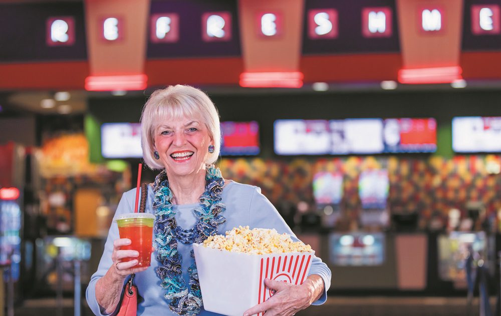 Senior woman at movie theater concession stand, popcorn