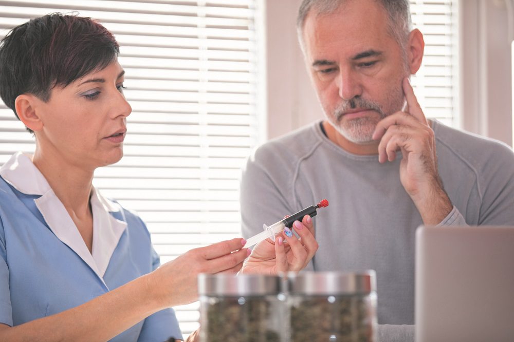 Healthcare Worker Explaining and Showing Cannabis Therapy Options To Costumer - Stock Photo