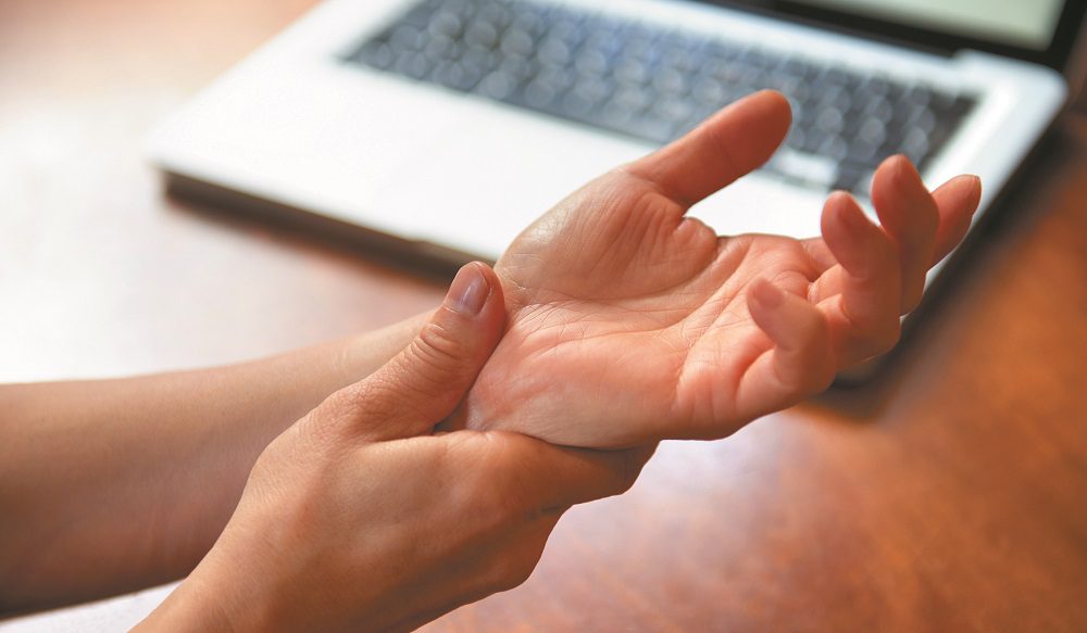 Woman massaging painful wrist at work repetitive strain injury
