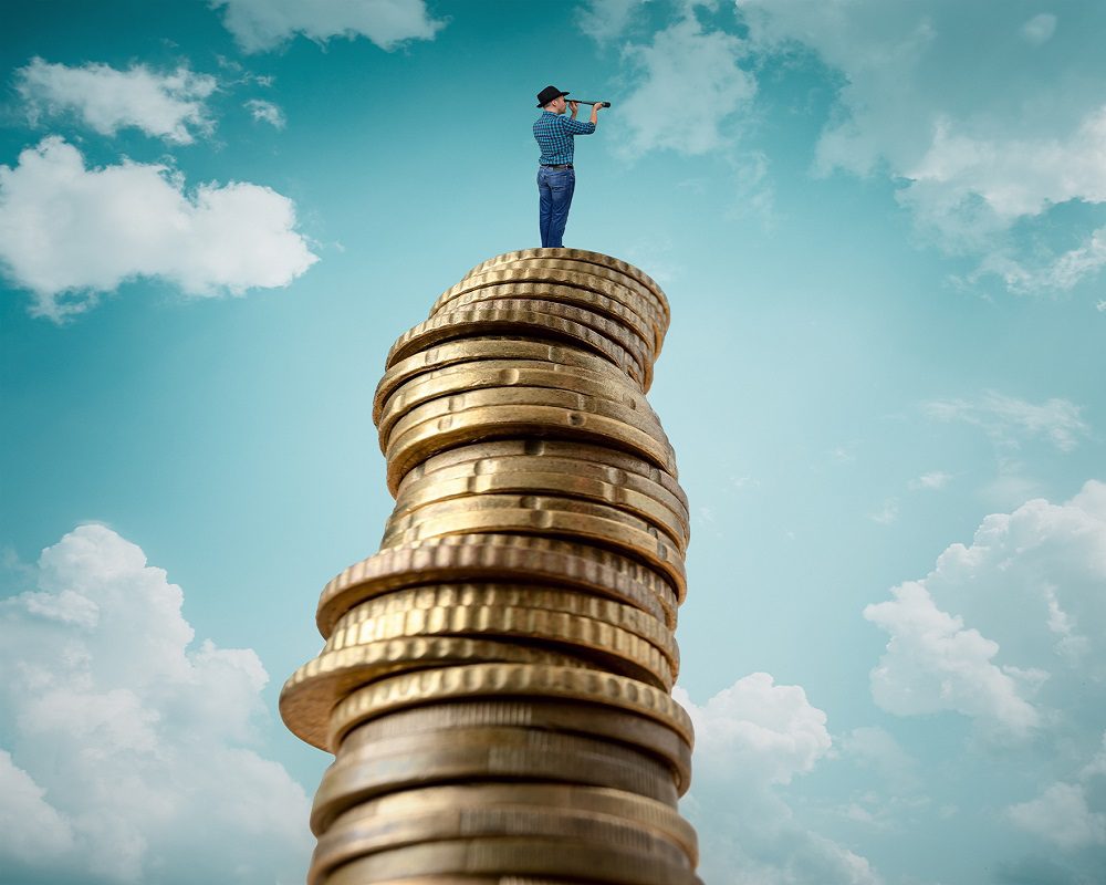 Man standing on stack of coins and looking at telescope