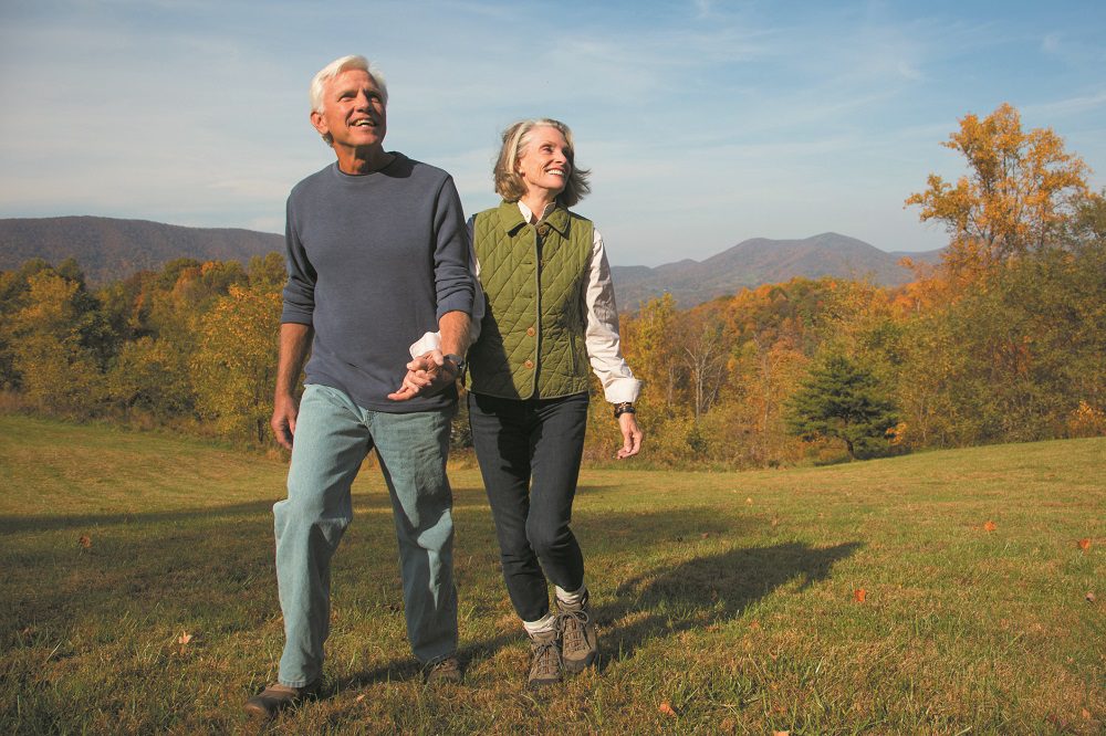 Older Caucasian couple walking in field