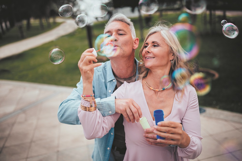 Playful mature couple blowing bubbles at the park