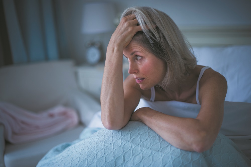 USA, New Jersey, Jersey City, Senior woman sitting in bed and suffering from insomnia