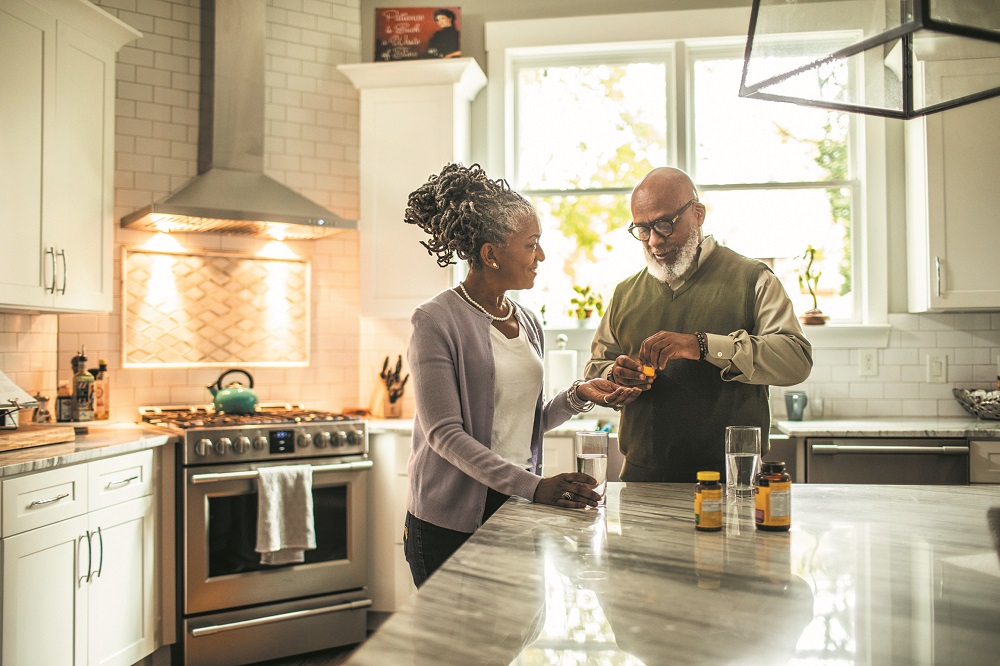 Senior couple taking vitamin supplements in kitchen of suburban home