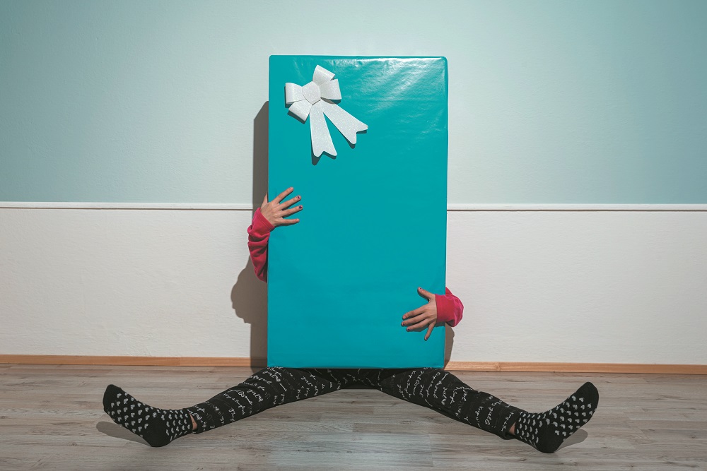 Little girl hiding behind a giant gift box