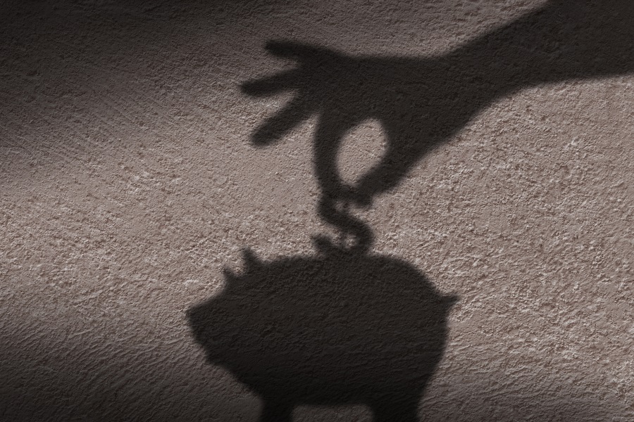 The shadow of hand putting a coin into piggy bank.