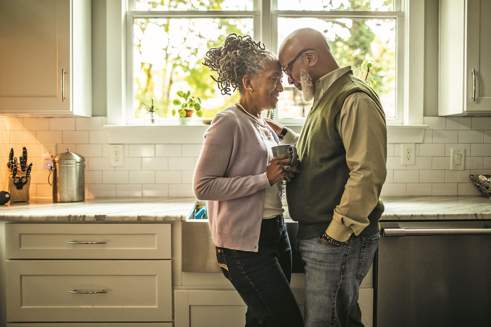 Senior couple embracing in kitchen of suburban home
