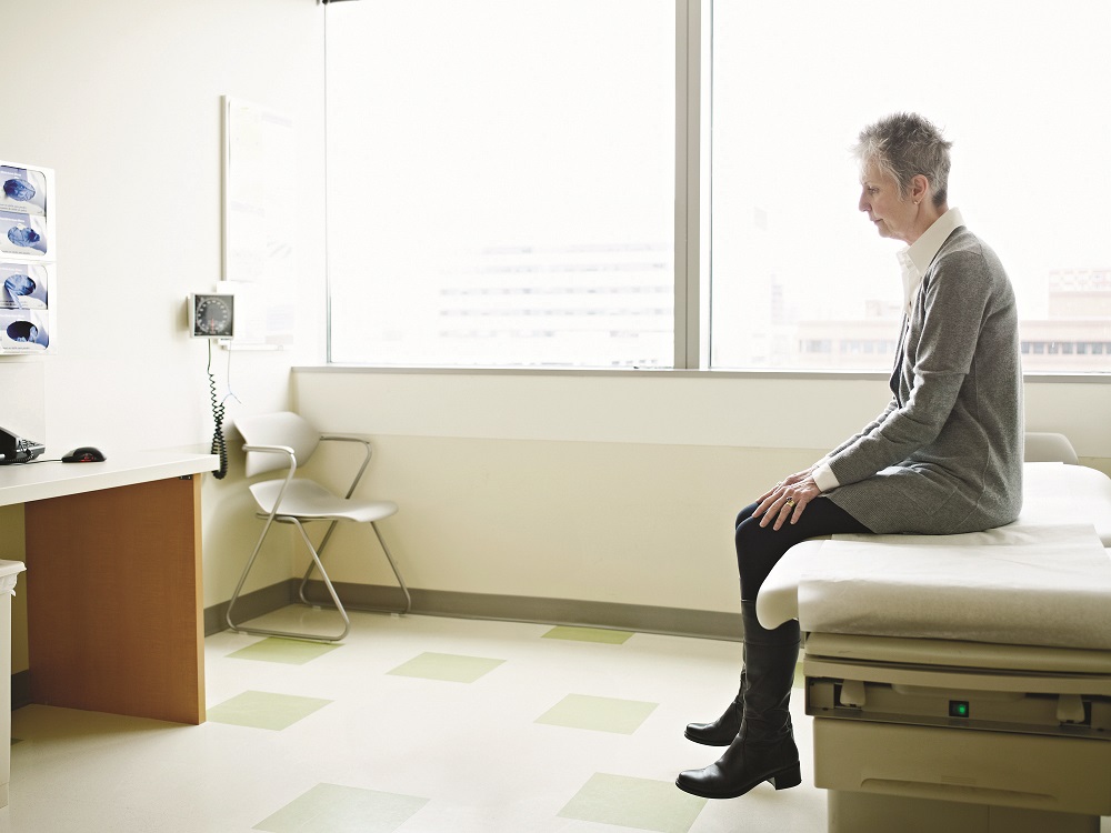 Female patient sitting on exam table in exam room
