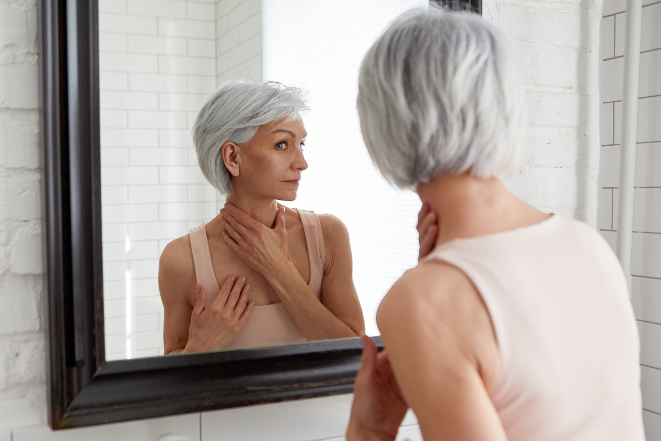 Elderly woman at mirror in bathroom