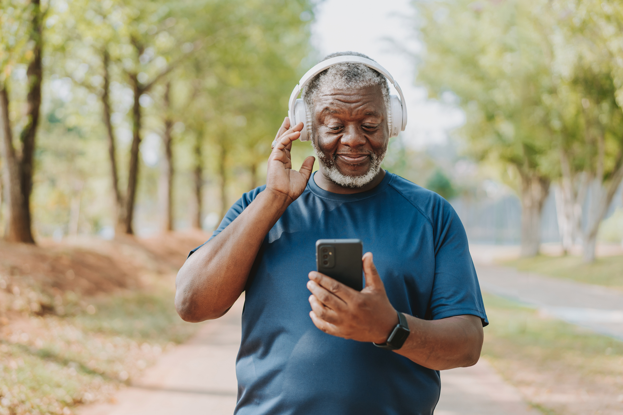 Senior man using smartphone while running in public park