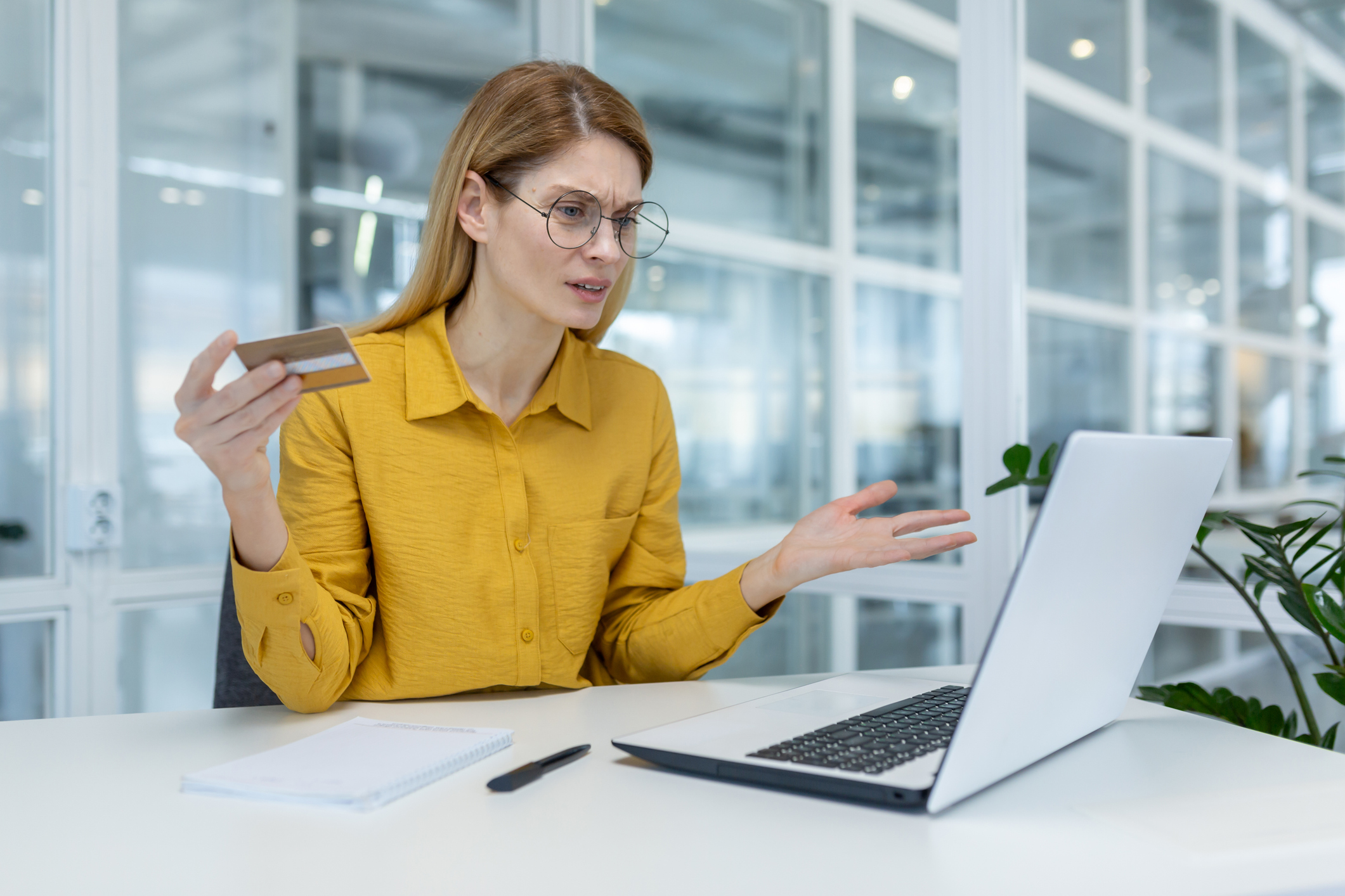 Concerned woman experiencing credit card issues while using laptop in office